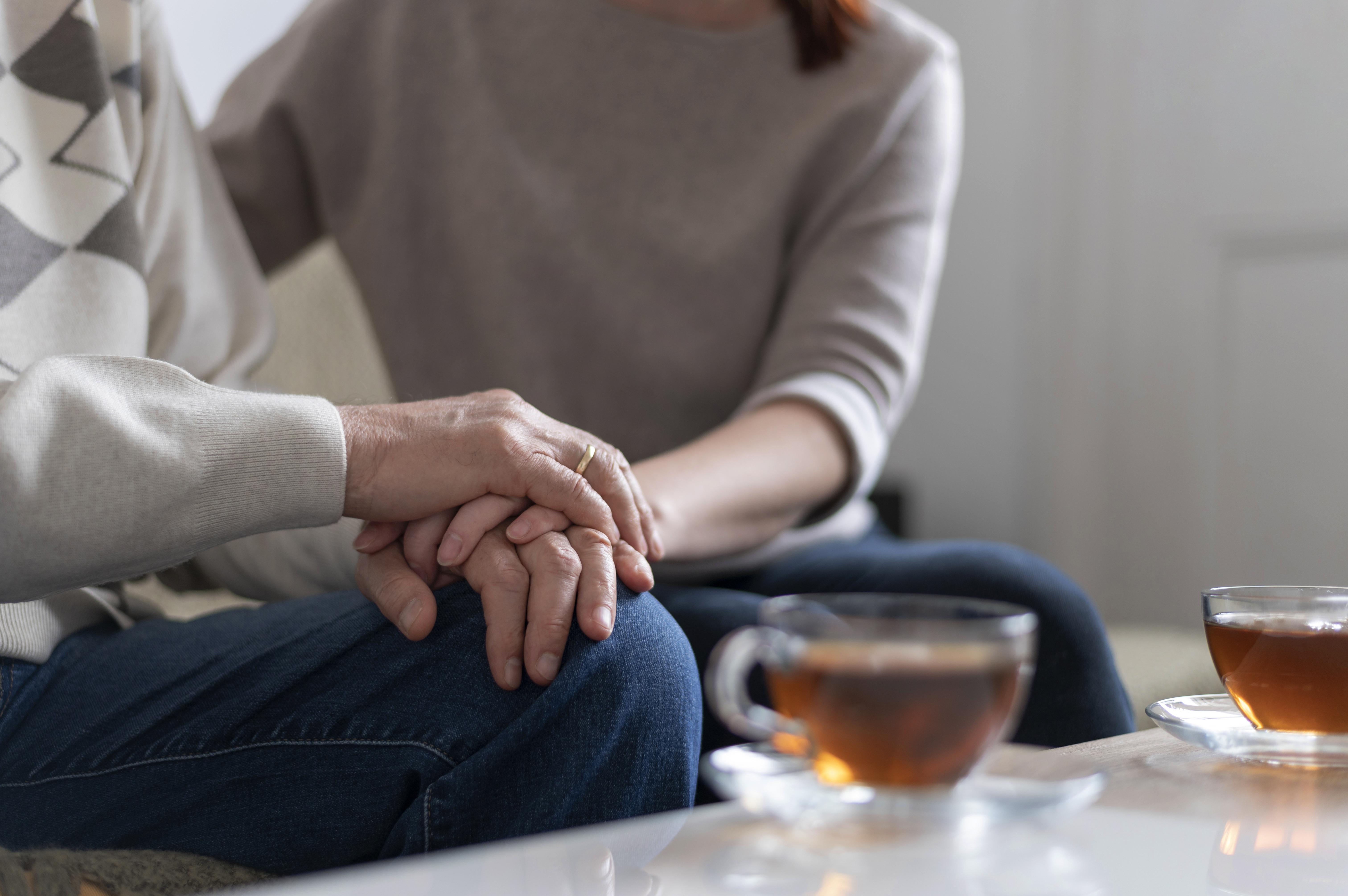 Dos personas sentadas dándose la mano en señal de apoyo